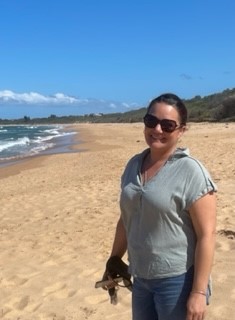 Smiling woman Karen Mills standing on a beach with blue sky