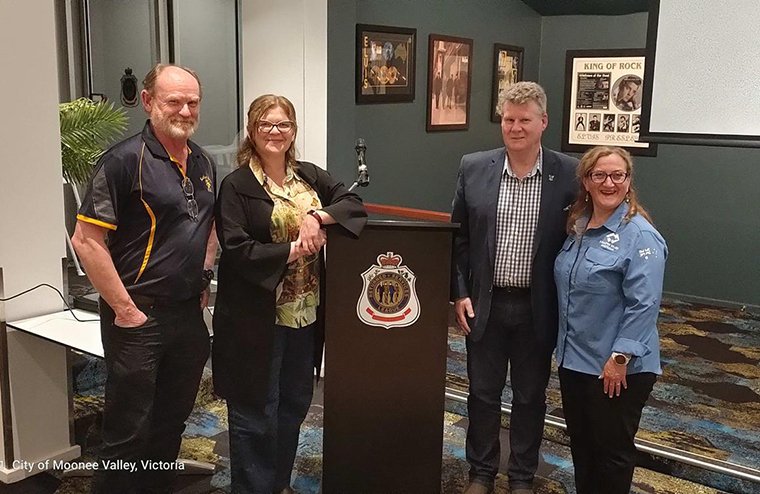 Four smiling people standing by a lecturn in an RSL