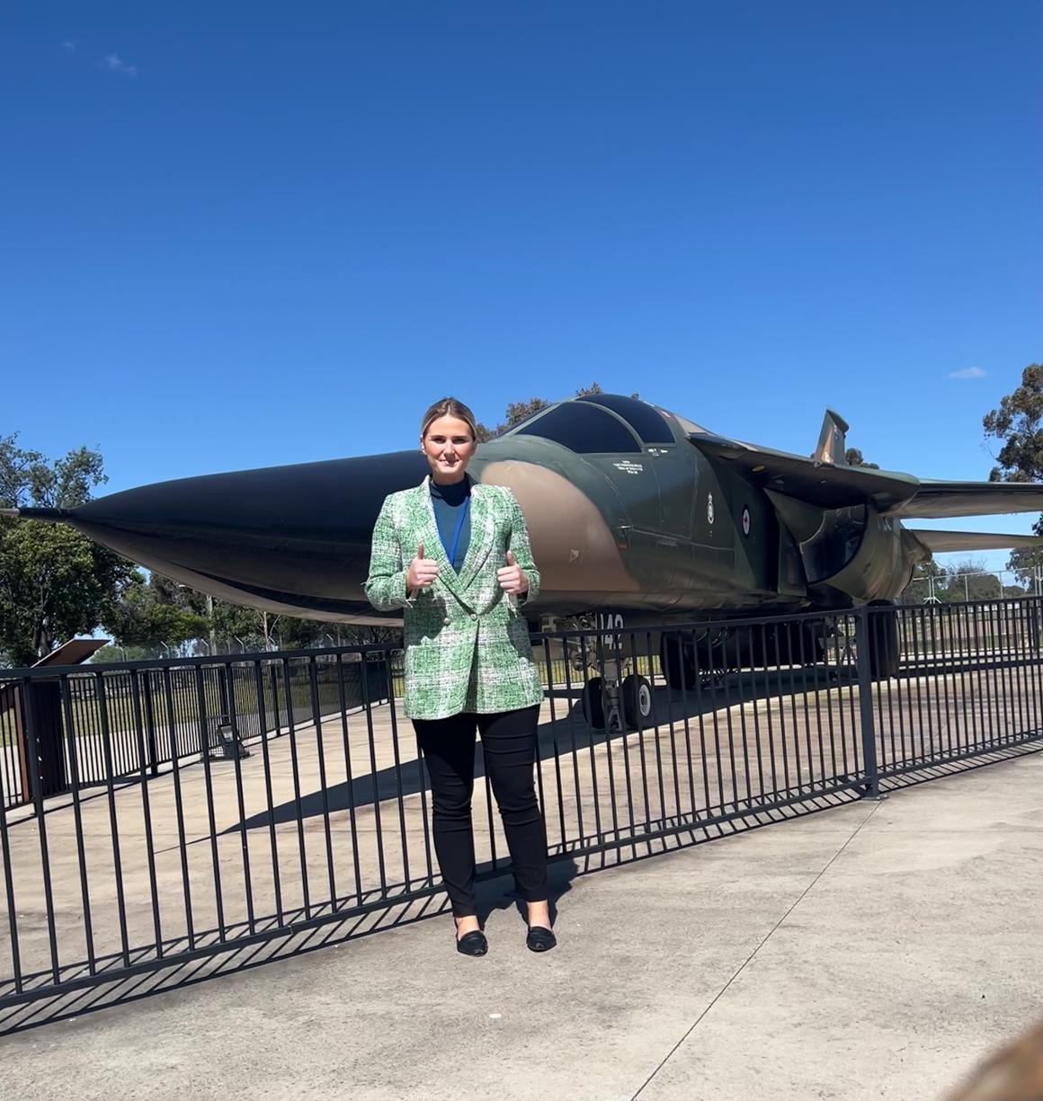 Smiling woman, Isabelle Whyte standing in front of a jet.