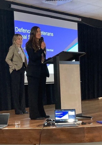 Two women with a microphone on a stage with lectern