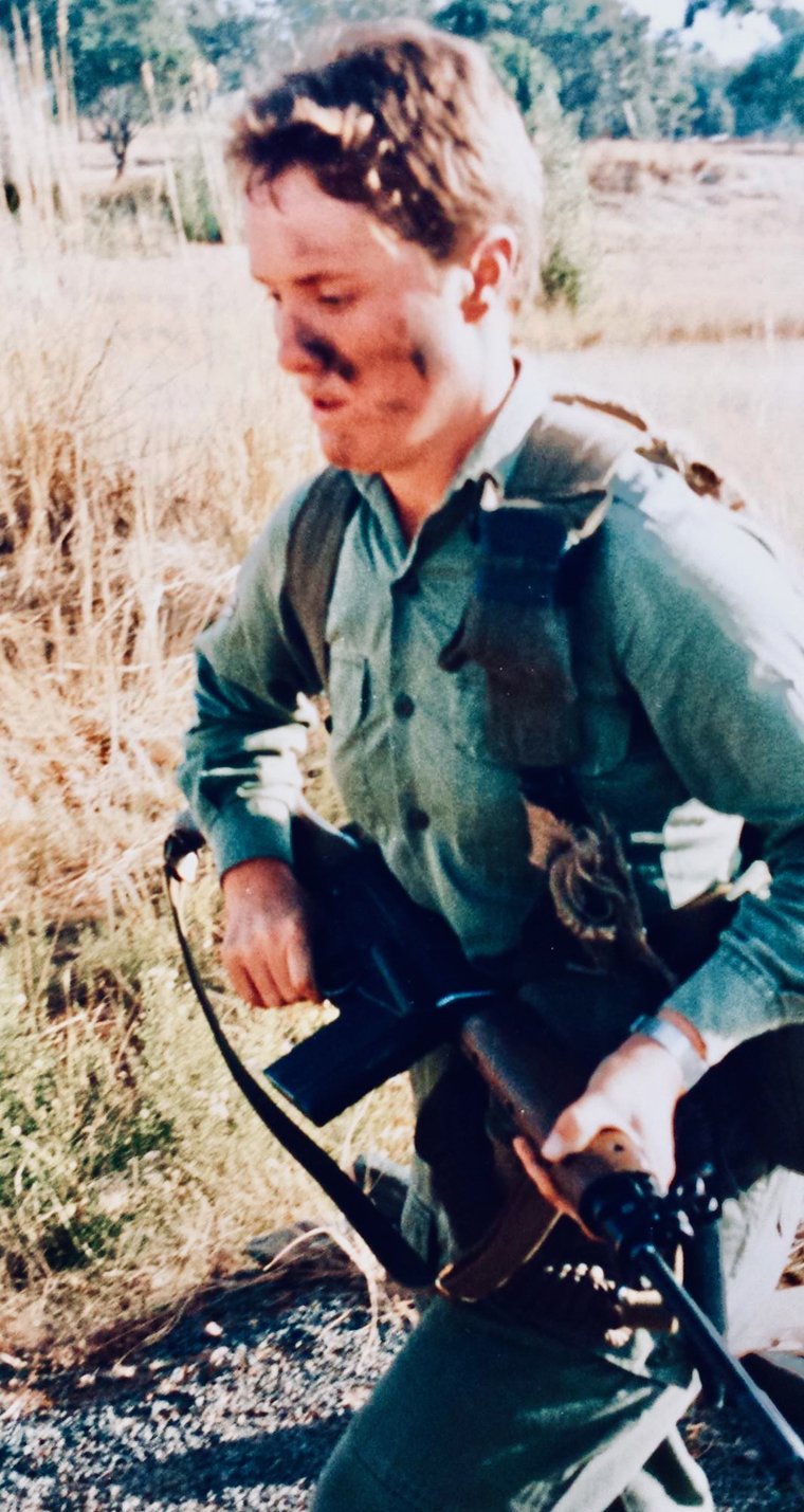 Woman in army uniform, Yvonne Sillett, running through grass holding gun